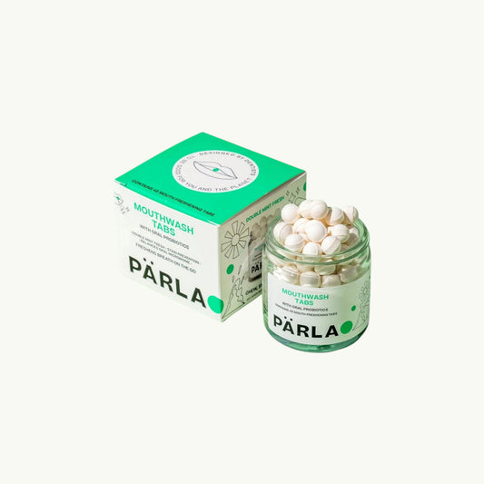 A jar of Pärla mouthwash tabs with white round tablets visible inside, shown next to its green and white product box on a solid light beige.