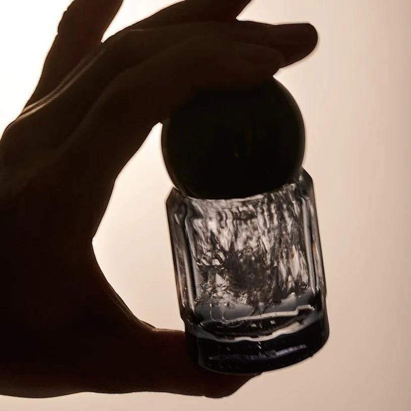 Rollr refillable roll-on deodorant in a glass bottle with a green aventurine roller ball held against backlight