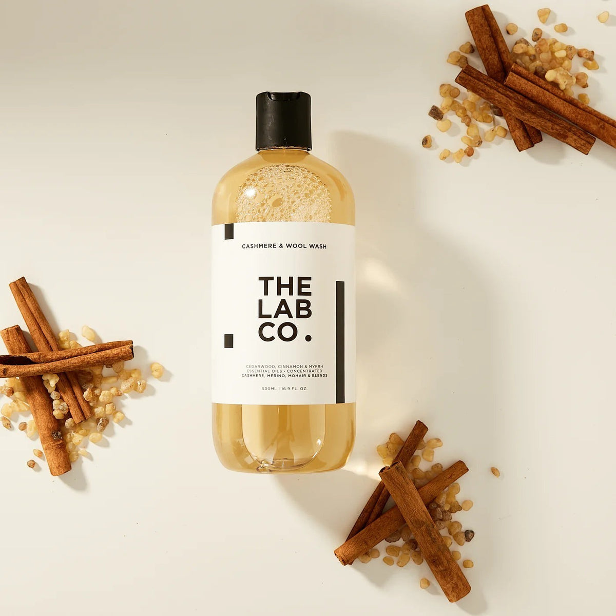The Lab Co cashmere and wool laundry detergent in a 500ml bottle surrounded by cinnamon sticks and myrrh resin