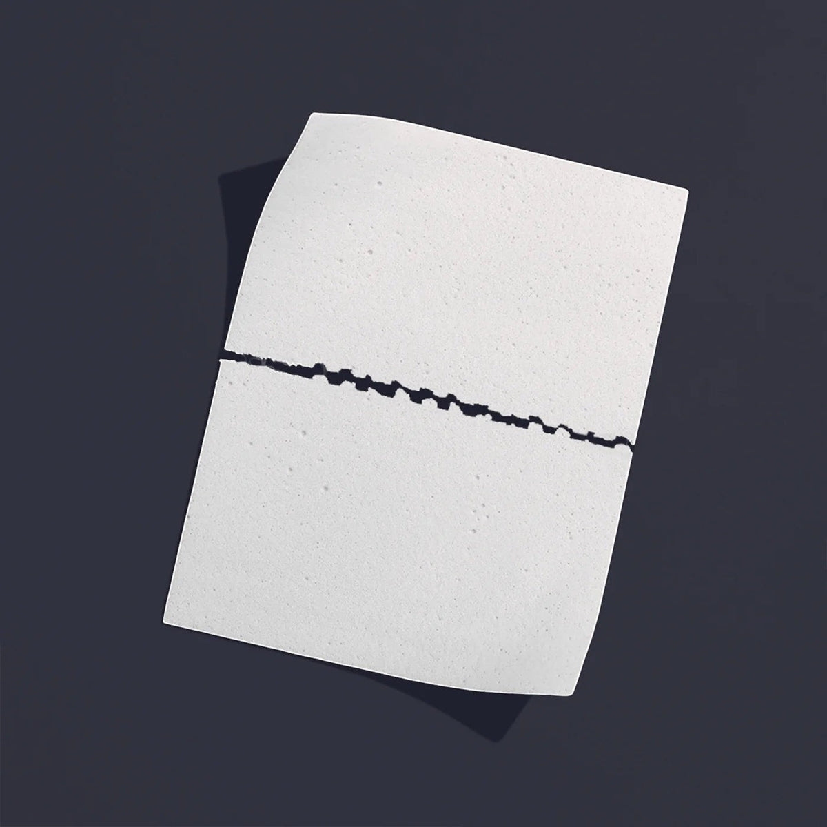 The Lab Co white laundry detergent strip with a perforated center line for easy tearing on a dark grey background