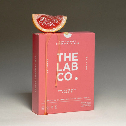 The Lab Co. Energising Laundry Detergent Strips in a pink box topped with a fresh grapefruit slice.