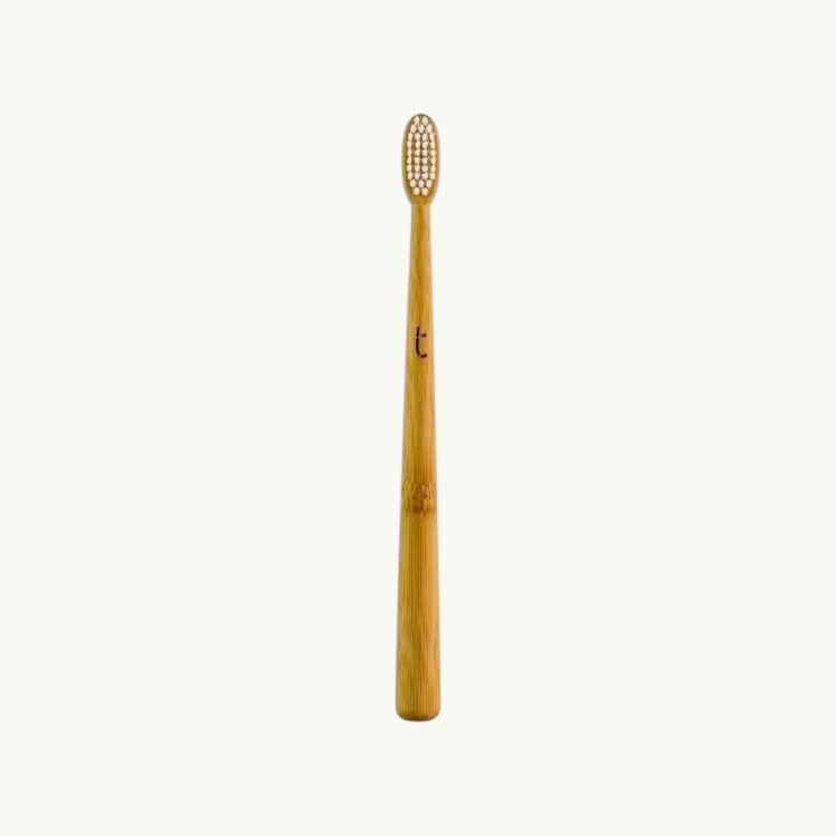 Truthbrush bamboo toothbrush with a slim head and soft plant-based bristles in a natural wood finish.