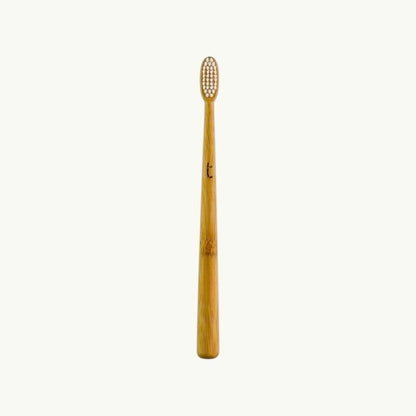 Truthbrush bamboo toothbrush with a slim head and soft plant-based bristles in a natural wood finish.