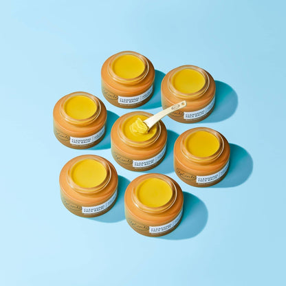upcircle natural cleansing balm in glass jars with a wooden spatula on a light blue background